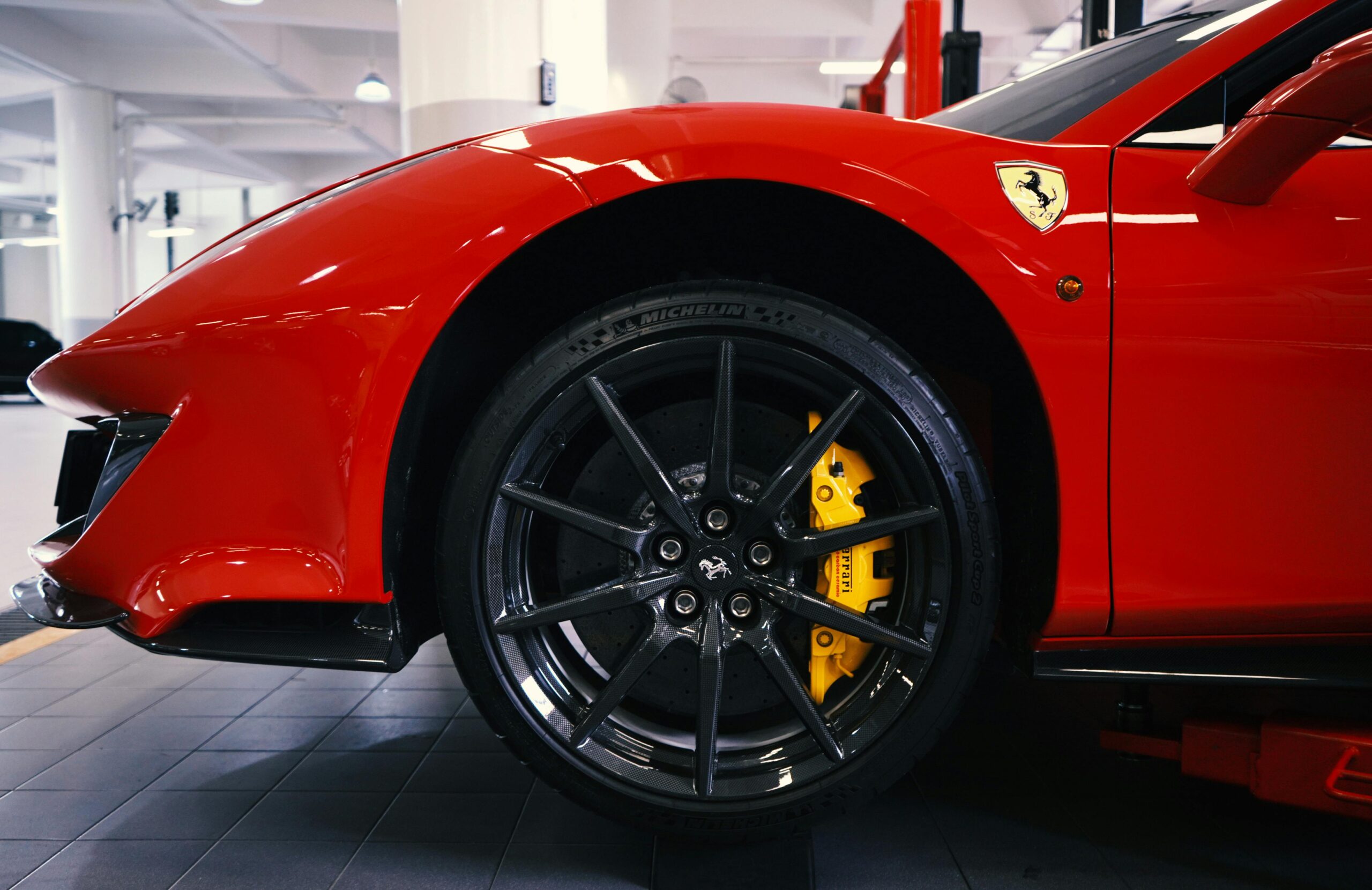 Detailed close-up of a red sports car wheel in a garage, highlighting the sleek design.