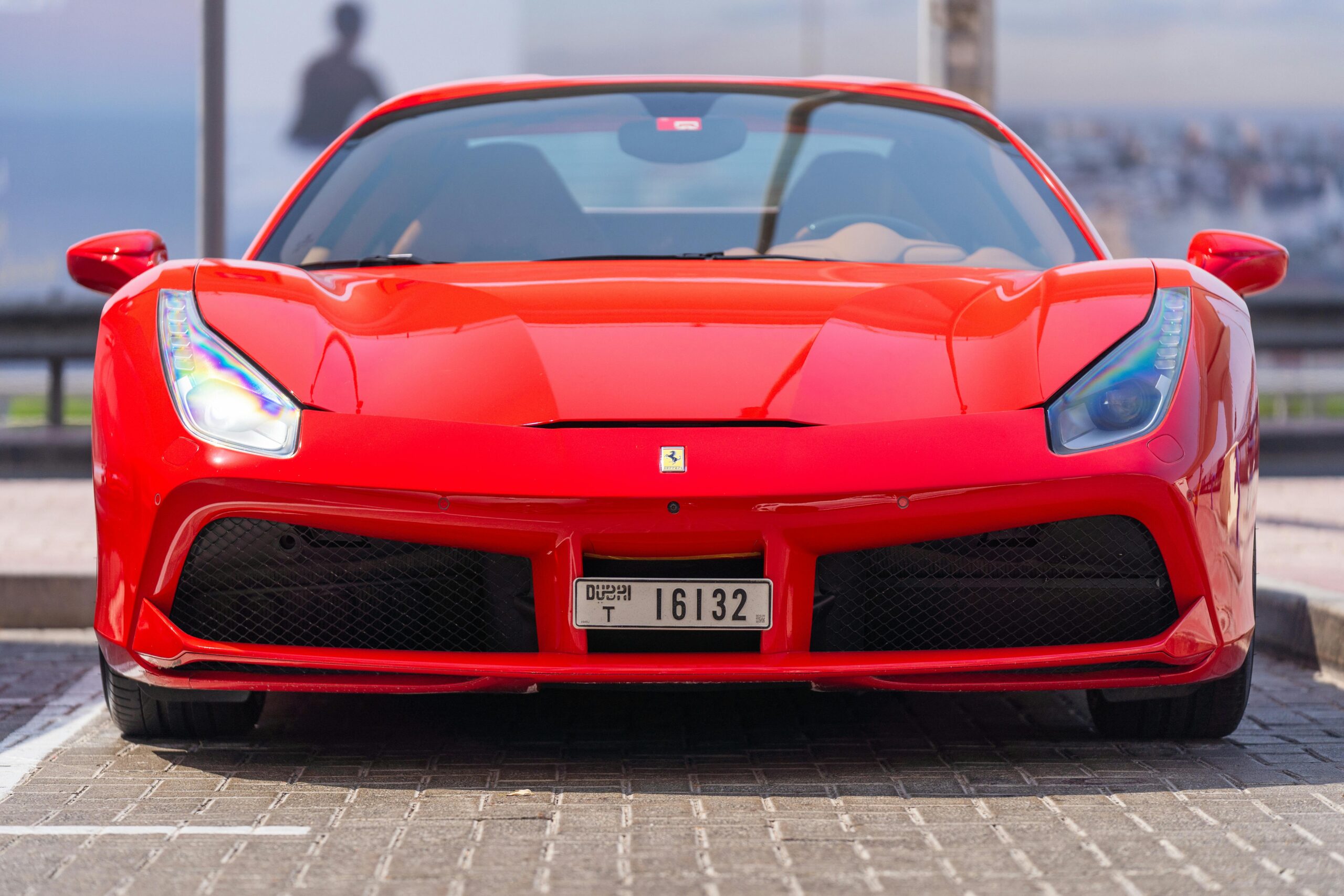 Front view of a sleek red sports car parked on a Dubai street.
